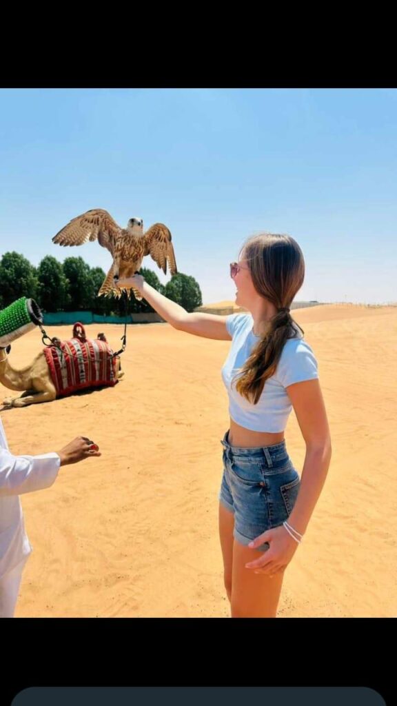 Woman holding a falcon during Dubai desert safari by Royal Viking Tourism.