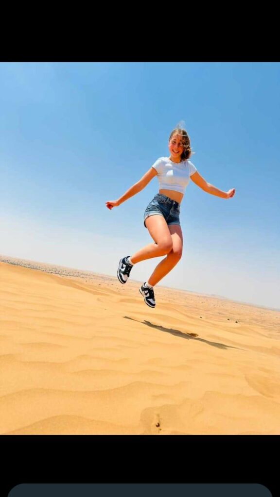 Woman jumping in the air during Dubai desert safari by Royal Viking Tourism.