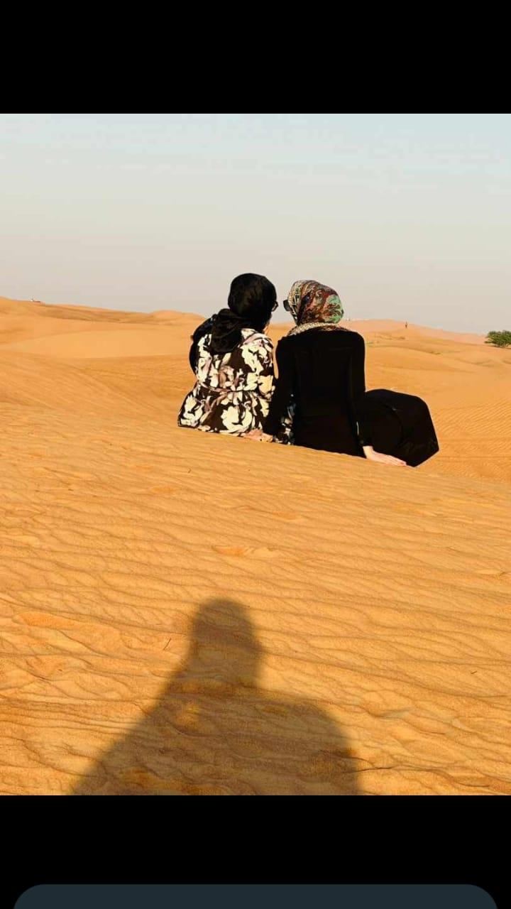 Two women sitting in the desert during Dubai desert safari by Royal Viking Tourism.