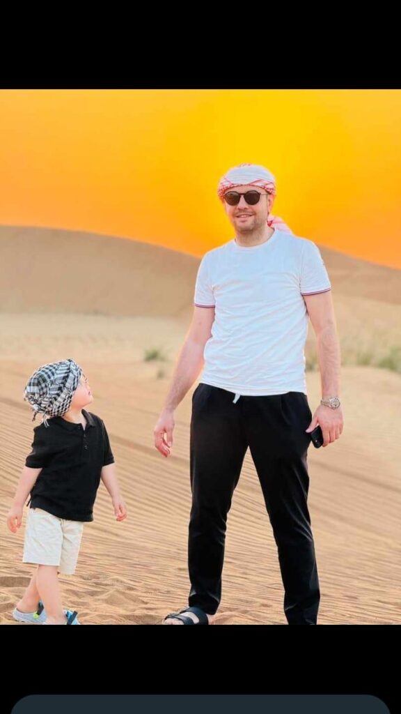 Father and son enjoying the Dubai desert sunset during a safari by Royal Viking Tourism.